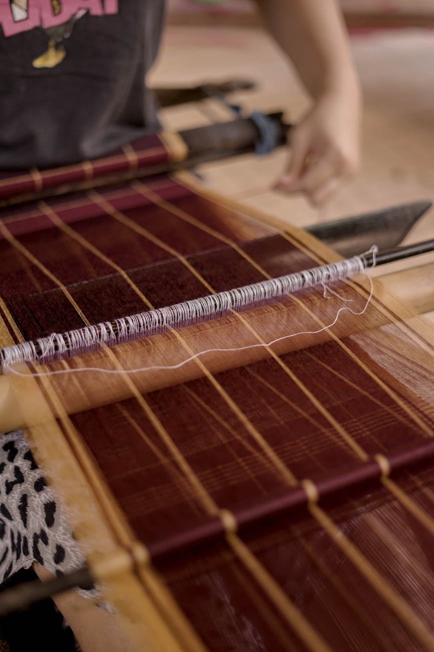 Local Balinese woman weaving traditional Endek textile on a wooden handloom in Sidemen